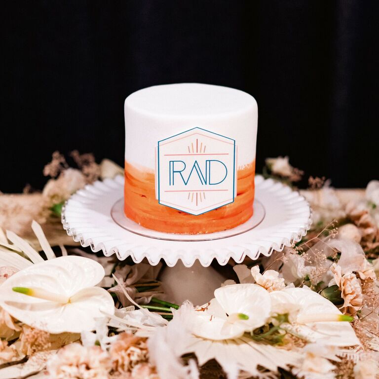 One-tier orange-and-white cake with modern monogram