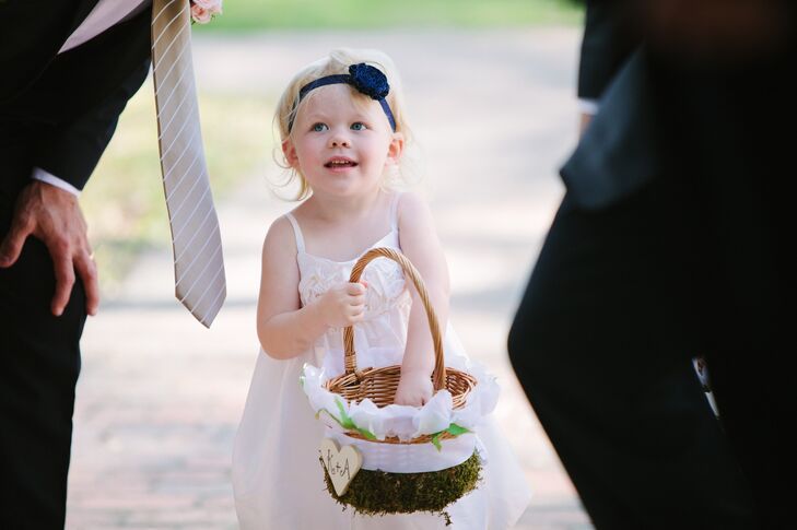 The couple's flower girl wore a white dress with a rosette detail and a rosette headband in navy to match their wedding colors.