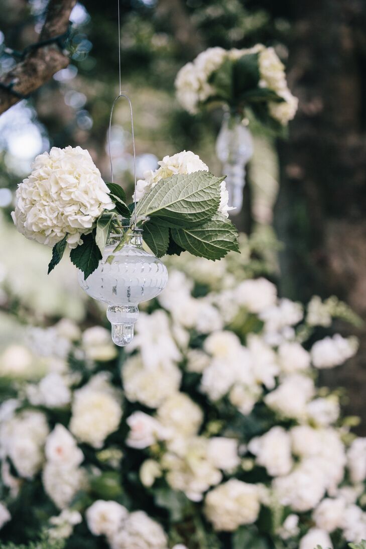 The couple hung glass vases filled with white hydrangea from the oak trees.