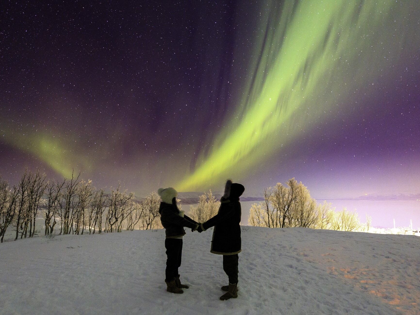 A couple watchs the aurora borealis (northern lights) near Björkliden Fjällby, Sweden