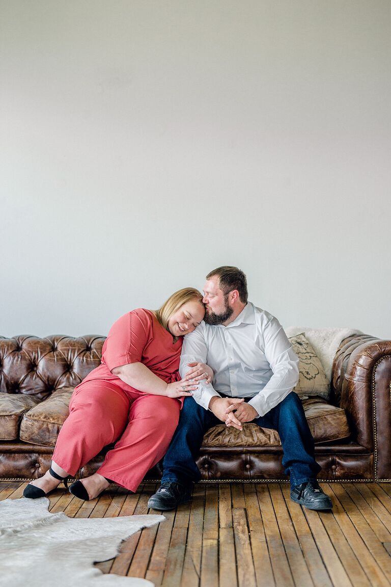 Couple cuddles on couch during engagement session