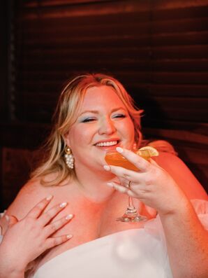 Bride With Drop Earrings, Soft Nail Polish and Blue Eye Shadow Sips Cocktail