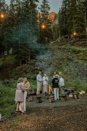 Bride and Family Members Around Outside Campfire at Rustic Wedding