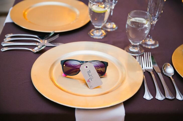 At the reception, plum-colored dining tables were set with gold plates and white napkins. The couple gave out neon sunglasses as wedding favors at each seat, which were used throughout the evening's festivities.