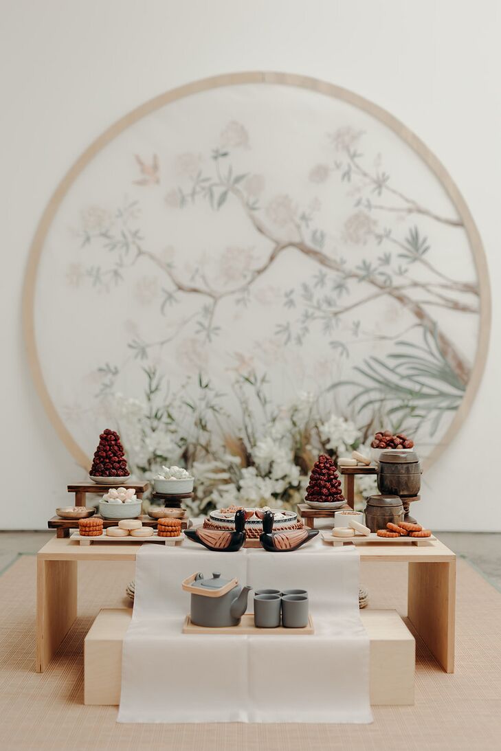 A delicate pastel backdrop hand-painted by the couple's wedding planner for a bride and groom's traditional Korean Paebaek tea ceremony, complete with a low table filled with sweets, for their wedding.