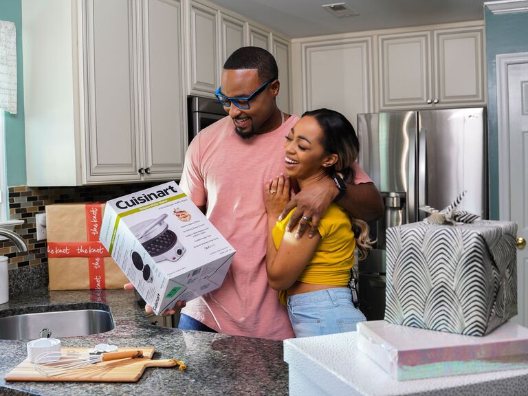 Couple smiling and opening wedding shower registry gifts from The Knot Registry