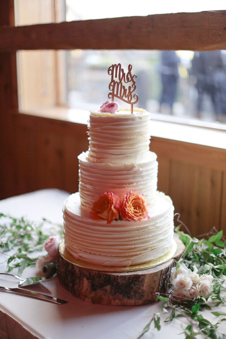 Nicole and Alex's three tier buttercream wedding cake was finished with fresh flowers, jasmine vine and a wooden Mr. and Mrs. topper.