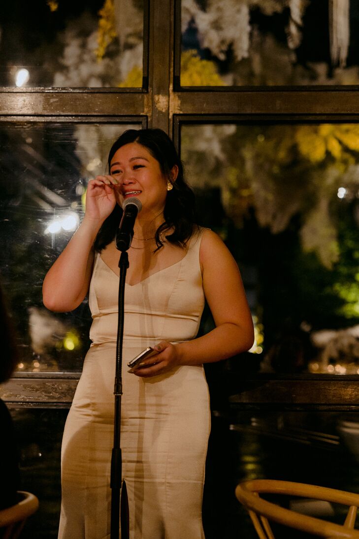 Bridesmaid in Fitted Satin Gown in Champagne Color Making a Tearful Speech at Nighttime Reception