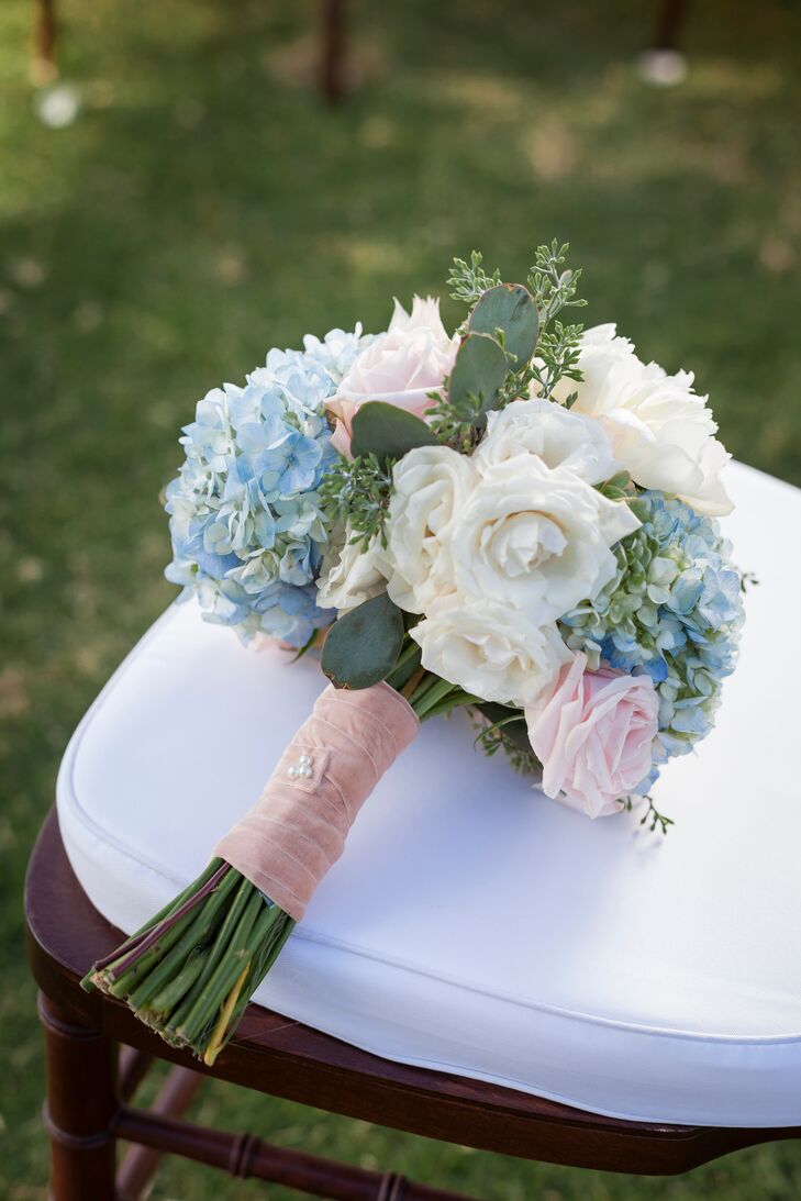Tara held an ivory, blue and pink bouquet filled with roses and hydrangeas. The bouquet had a pink wrap.