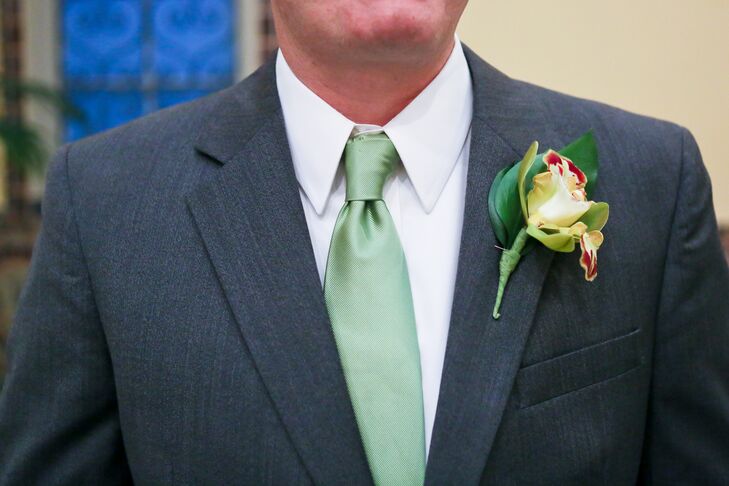 The groom wore a dark gray tuxedo with a green tie, and had a yellow lily pinned to the jacket.