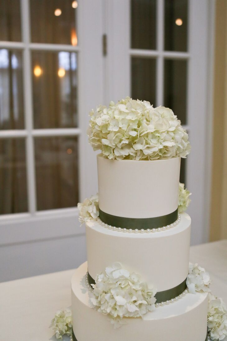 The ivory wedding cake had green ribbon wrapped around the base of each tier, and was accented with ivory hydrangeas.