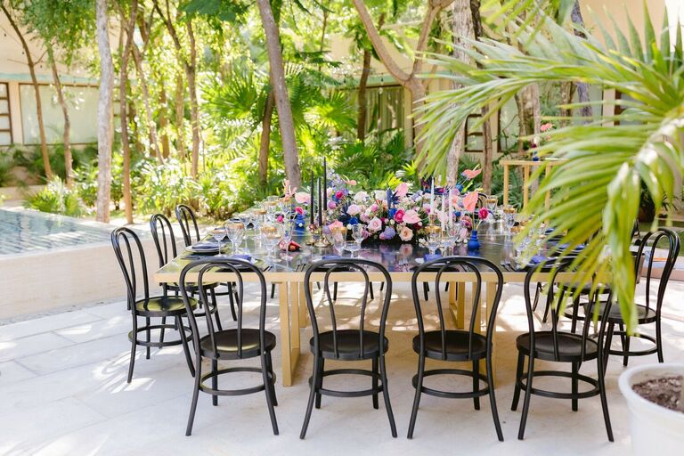 Glam beach reception with black bentwood chairs and gold table
