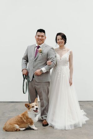 Bride in Tulle A-Line Gown, Updo, and Groom in Gray Suit Pose With Their Corgi Dog