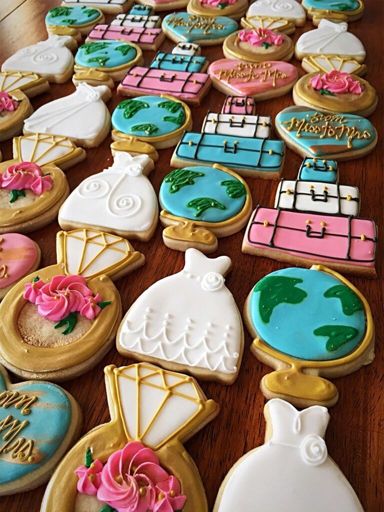 Cookies decorated colorfully as globes, wedding dress, wedding ring, luggage, etc.