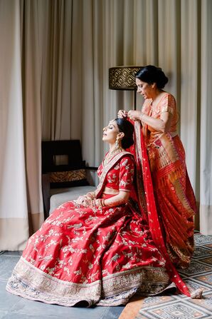 Mother of Bride Helping Bride Put on Red Wedding Lehenga and Veil