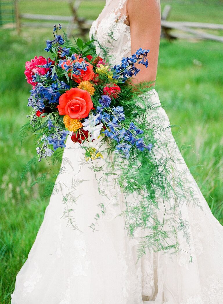 bride holding red bouquet with cascading greenery