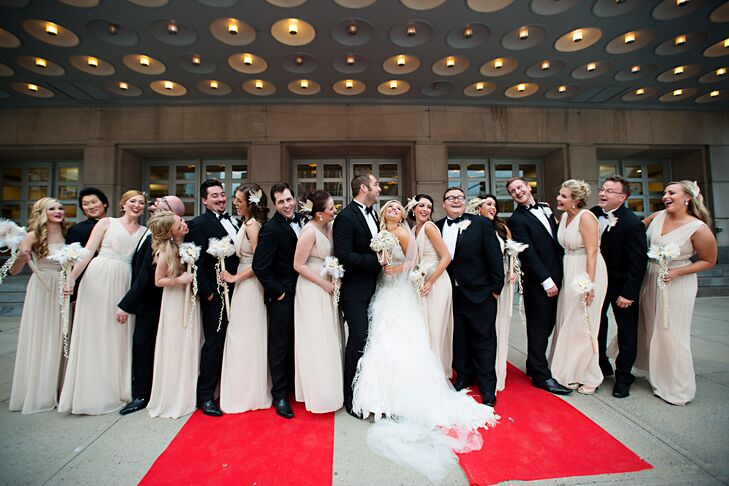 The bridesmaids wore champagne floor-length chiffon dresses with rhinestone belts and 1920s-inspired rhinestone and feather headpieces. The groomsmen wore black and white formal tuxedos to also match the 1920s look.
