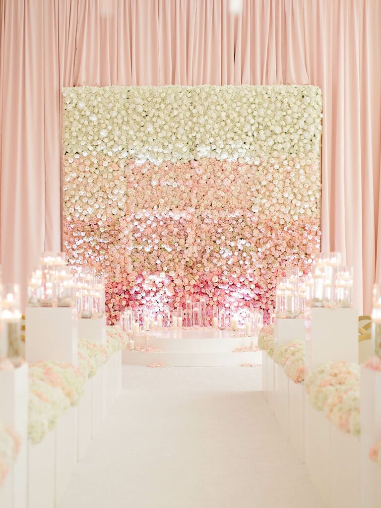 A large white and pink flower wedding backdrop at a ceremony. 
