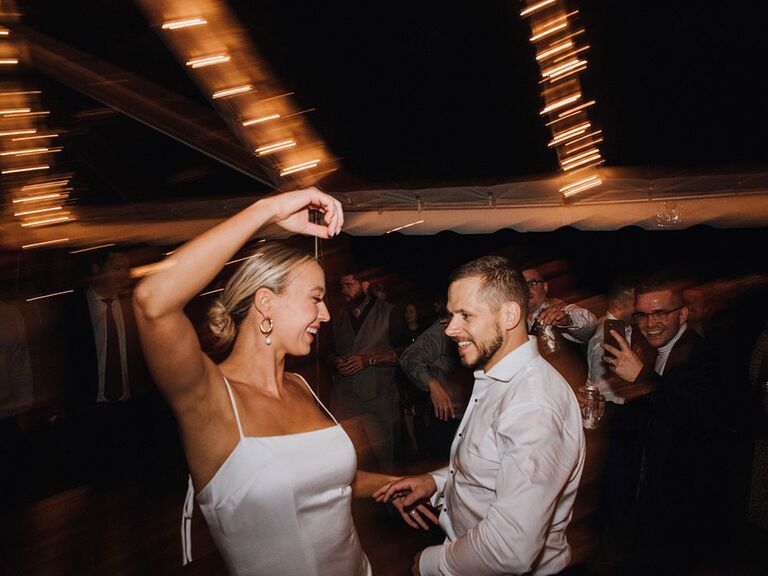 Bride in '90s slip wedding dress dancing with groom at reception