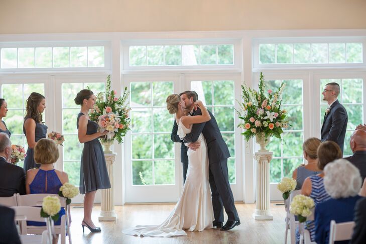 Decor at the ceremony featured pedestal flower arrangements of white delphinium, peach hyacinth, peach ranucnulses, pink roses and white lilies placed on white pillars at the altar.