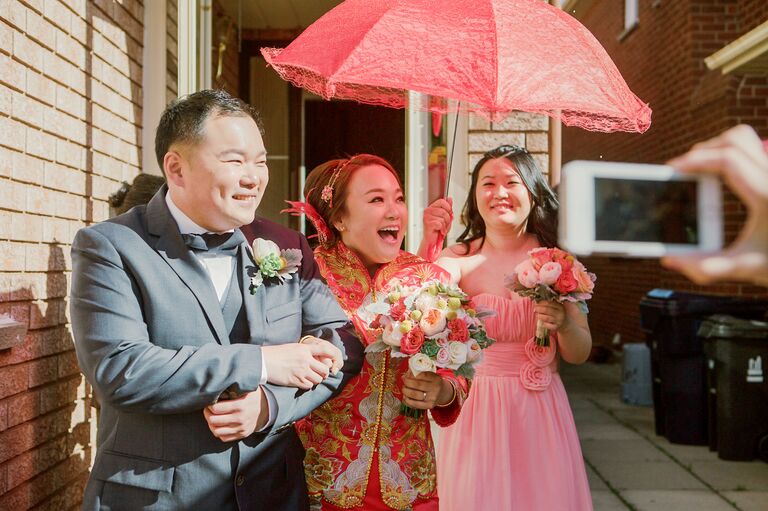 Bride walking under red fan during Chinese wedding