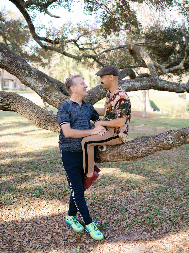 Couple poses with a tree at their local park. 