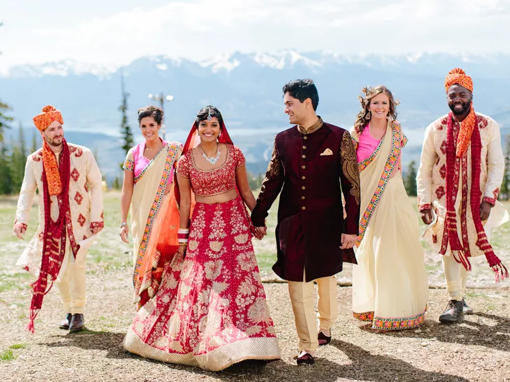 Indian couple and their wedding guests smile at the camera. 