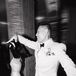 Black-and-White Photo of Groom in White Suit Twirling Bride on Dance Floor