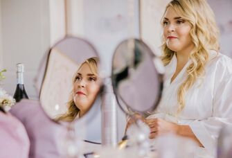 Bride glances in mirror while getting ready for her ceremony. 