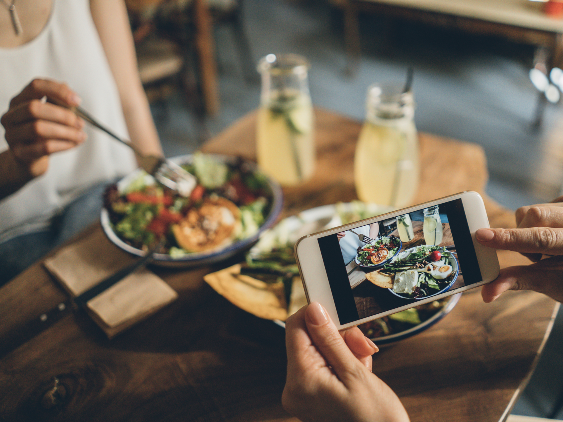 man taking photo of girlfriend at dinner
