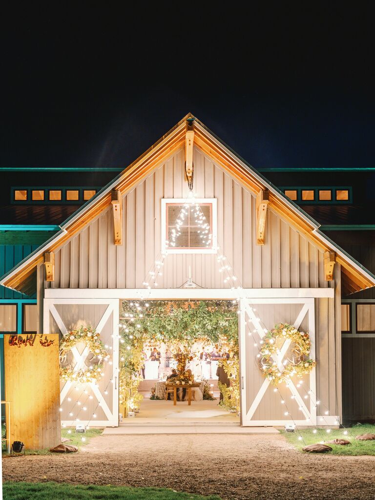 exterior of barn wedding venue decorated with string lights from the roof to the ground