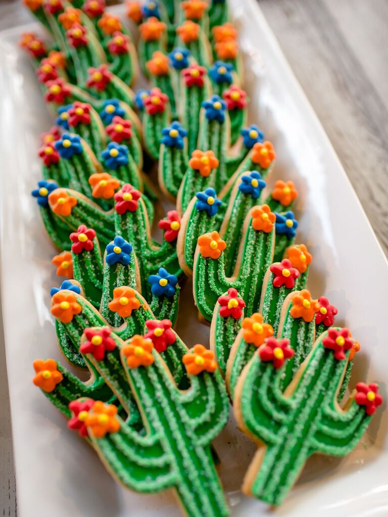 Colorful cactus-shaped cookies decorated with bright flowers and sparkling sprinkles. 
