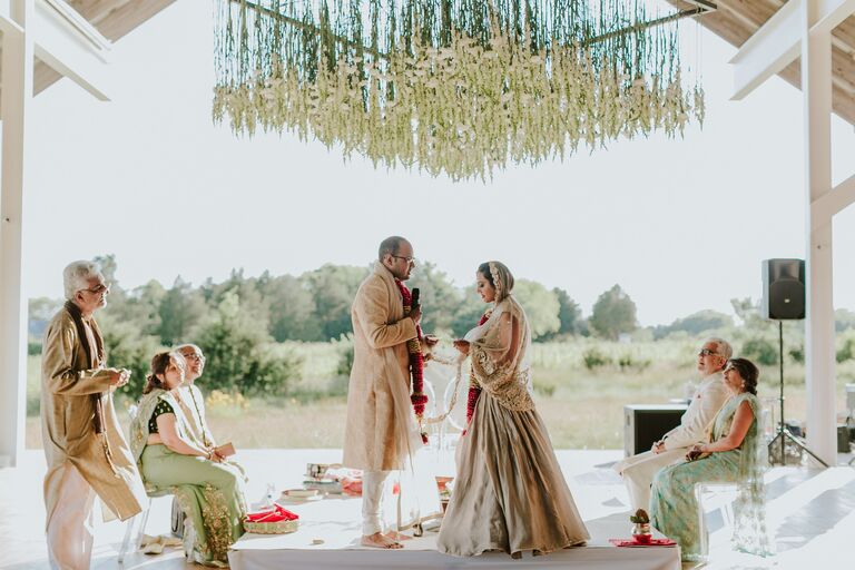 Couple under modern mandap with hanging flowers