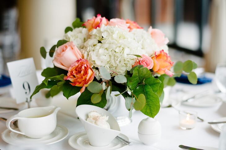 Coral roses and textured greenery added a splash of fresh color to the reception tables.