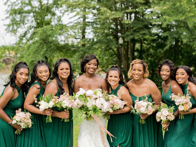 A bride and her wedding party hold pale pink and white bouquets.