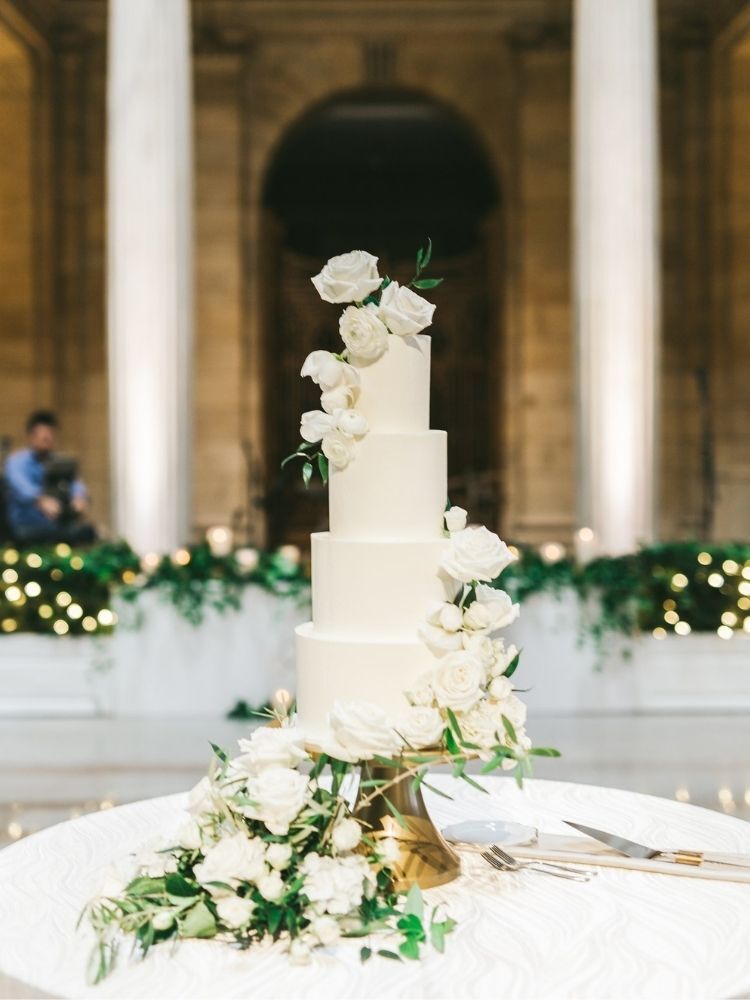 elegant white wedding cake decorated with white roses and greenery