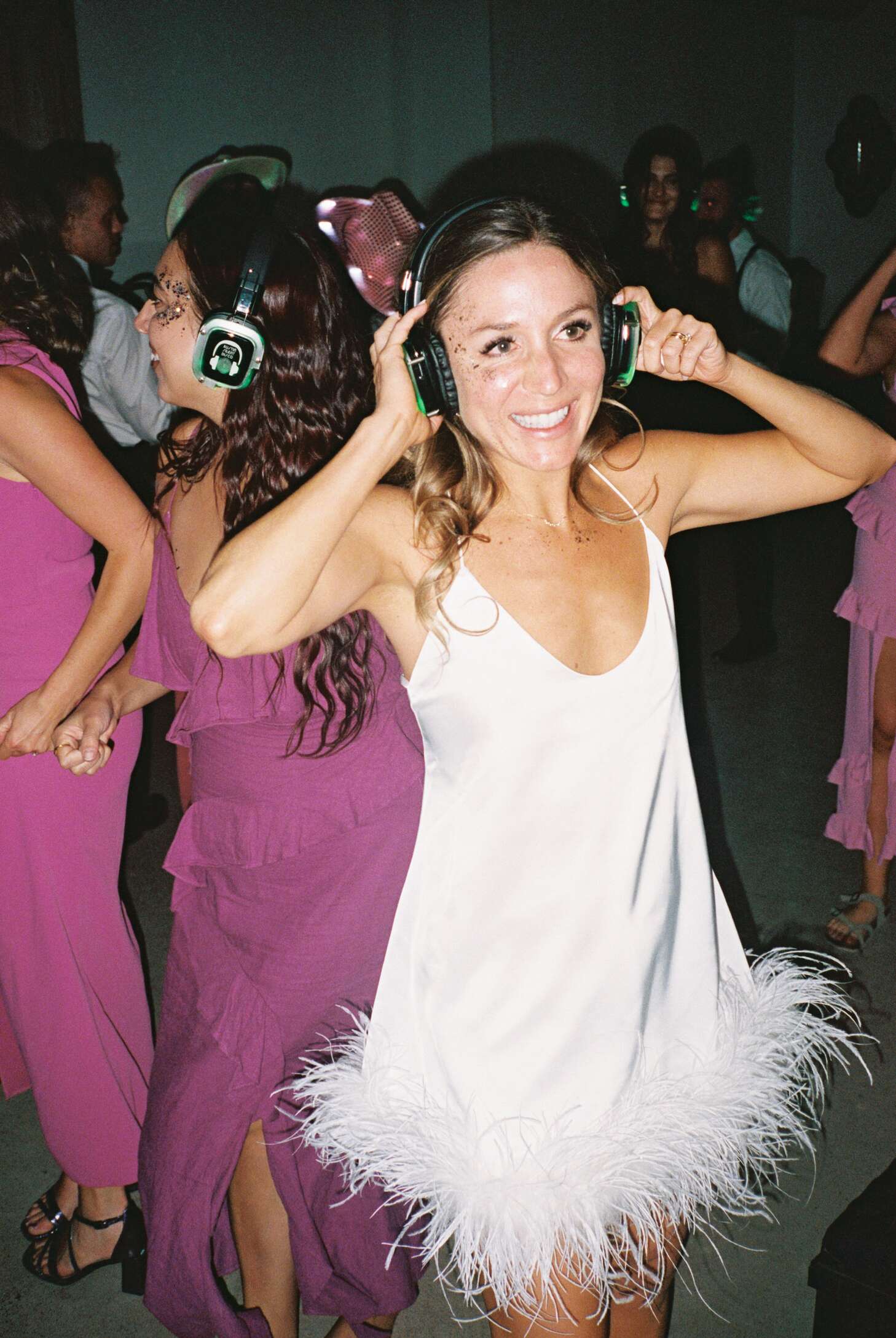 Bride in Mini Dress With Feather Ruffles Dances With Headphones at Silent  Disco Reception