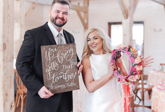 Groom holding sign and bride holding tourbine bouquet. 