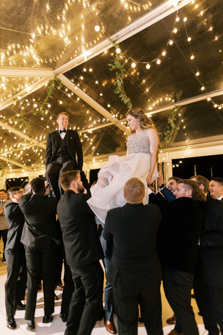 Bride and Groom Lifted by Male Wedding Guests, Jewish Dance Tradition, Tent and String Lights