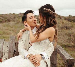 Bride with twisted half-up hairstyle sitting in groom's lap