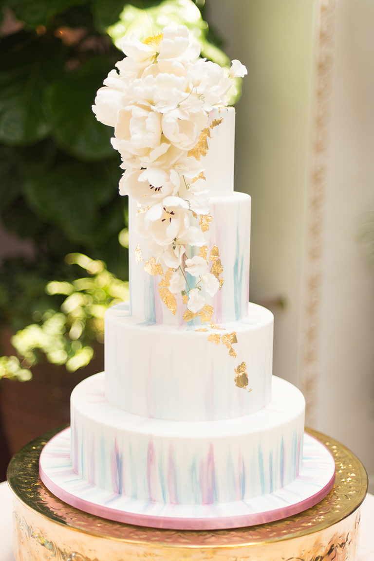 White wedding cake with watercolor designs and gold leafing