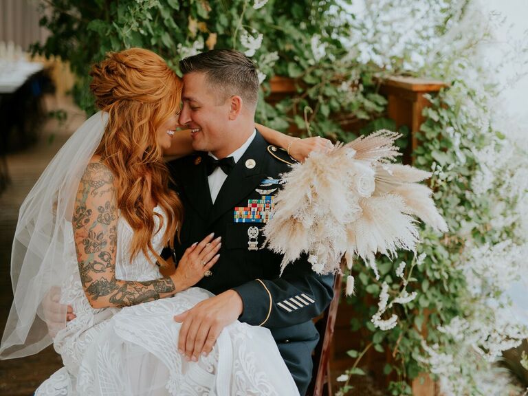 bride with tattoos hugging groom in military uniform