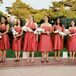 Emily's eight bridesmaids chose guava-colored tea-length dresses with brown sashes in various styles. Each carried large bouquets of branches wrapped with oversized white orchids.