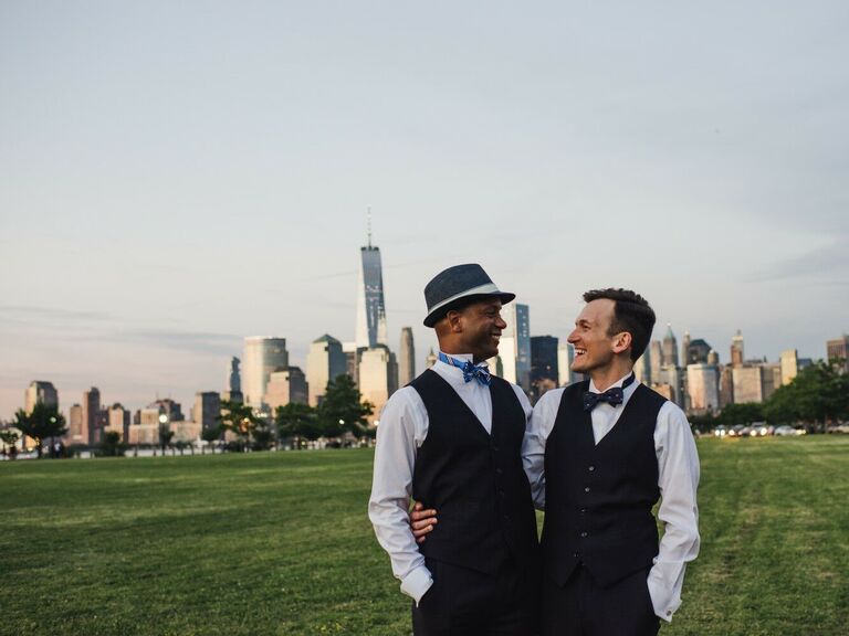 Grooms smile at each other in front of the New York City skyline. 