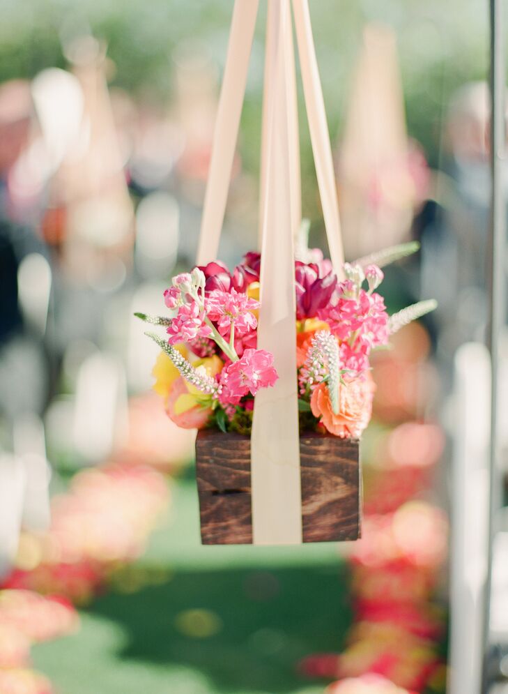 "I had very simple ceremony decorations. We had sunset-colored petals (magenta, yellow, orange) along the sides of the aisle. In addition we had shepherd hooks lining the aisle with small wooden boxes filled with green amaranthus, jasmine, yellow and orange ranunculus, plum tulips, assorted succulents and veronica. It was the perfect accessory to an already gorgeous desert backdrop."