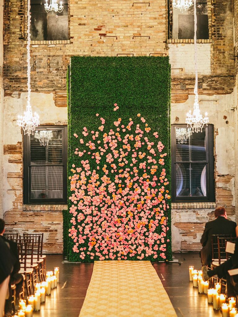 A tall green and peach wall of flowers at a couple's wedding ceremony. 
