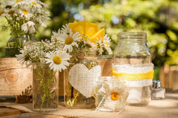 White daisies and yellow roses filled glass mason jars that served as table centerpieces.