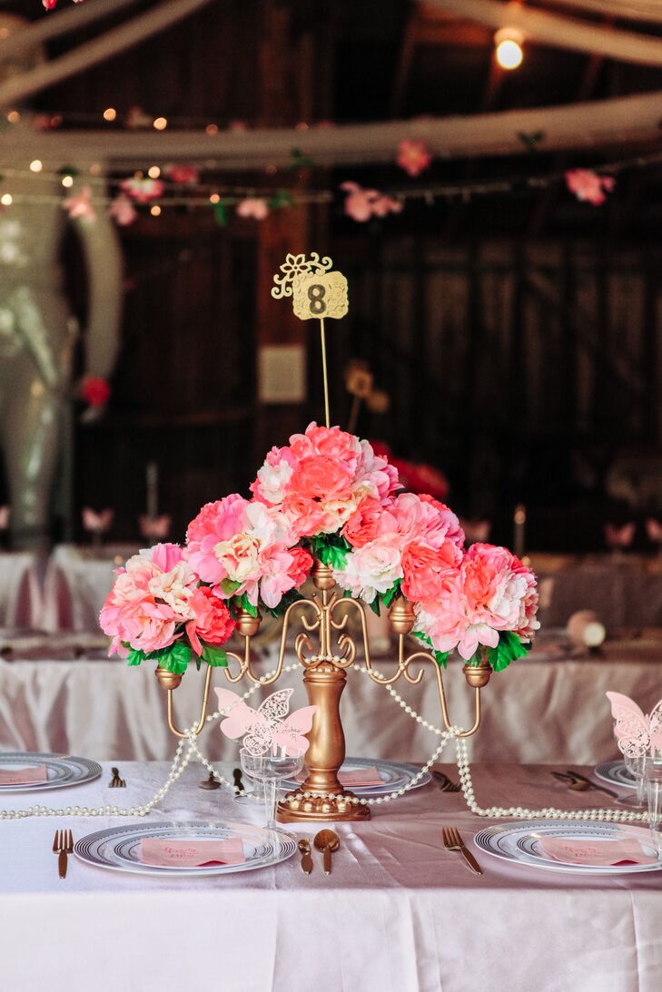 The long dining tables at the reception were decorated with gold candelabras topped off by pink peonies and alstroemerias with pearls dangling from it.