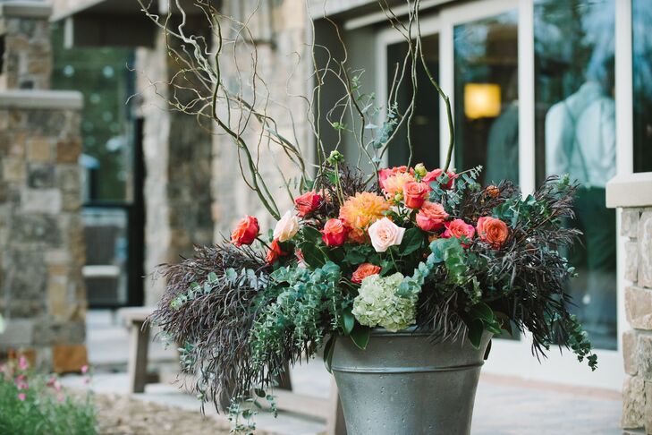 Rustic floral arrangements with whimsical willow branches, brightly colored roses, eucalyptus and a mix of grasses were placed at the entrance to the ceremony.