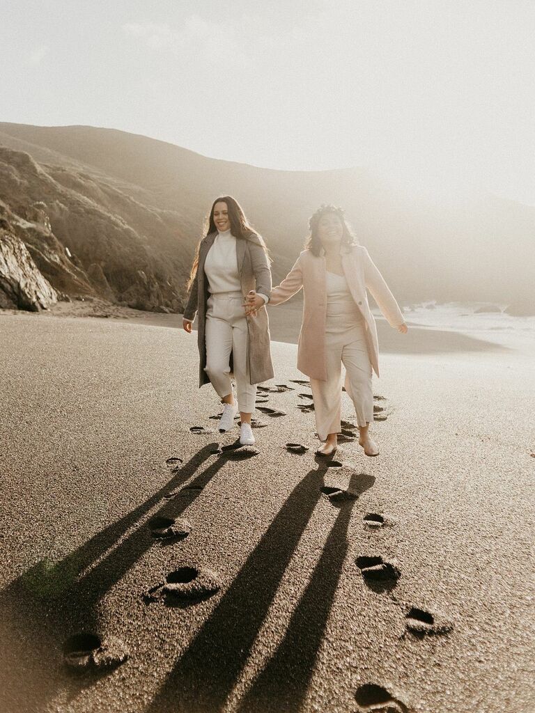Couple walks hand in hand down the beach at sunrise. 